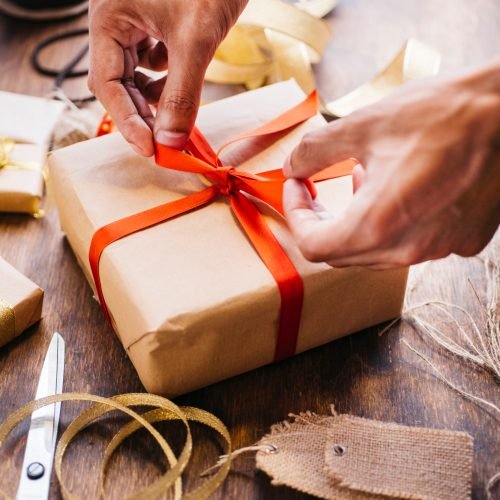 person-tying-bow-gift-box